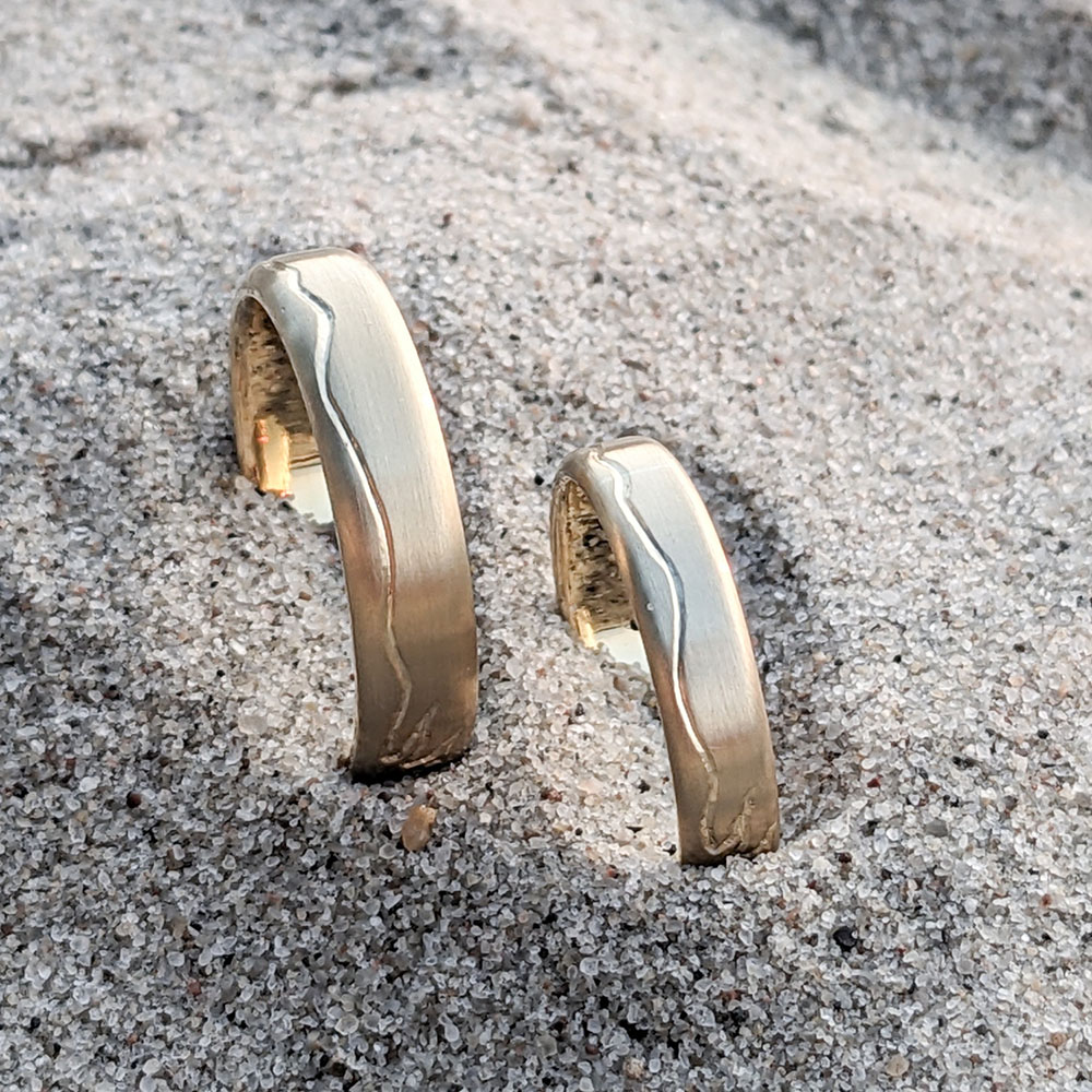 750 kullast abielusõrmused lainelise joonega liivasel looduslikul taustal