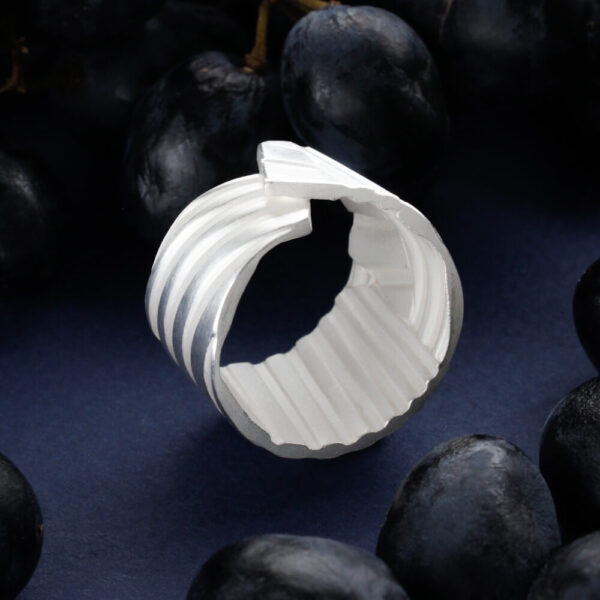 hõbedast triibuline sõrmus avatud geomeetrilise disainiga tumedal taustal