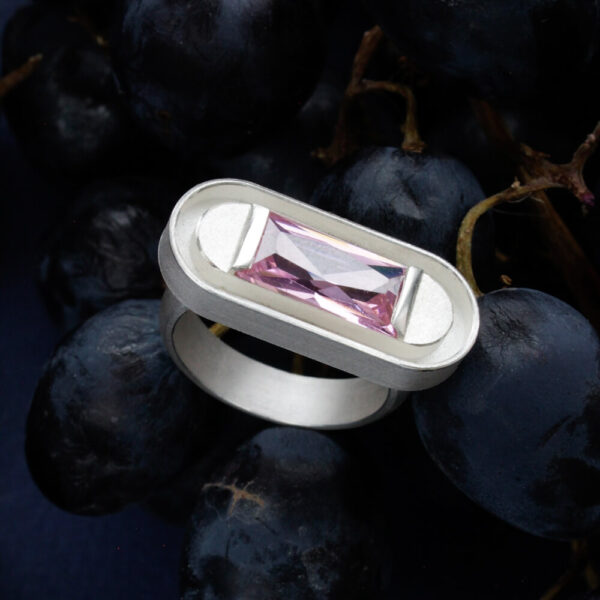 hõbedast sõrmus pikliku roosa kiviga, modernne käsitööehe viinamarjade taustal